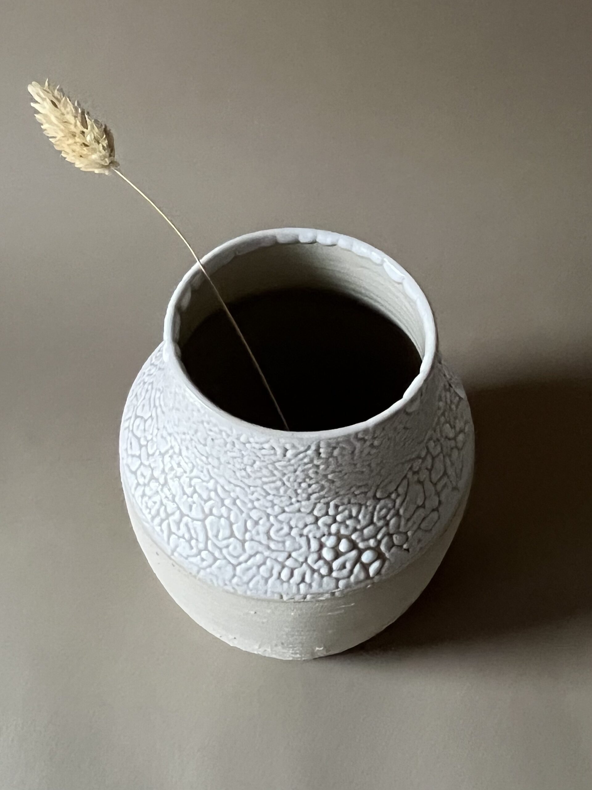 Vase Winter rond en grès blanc, col émaillé blanc rétracté, garni d'une graminée, vue de face