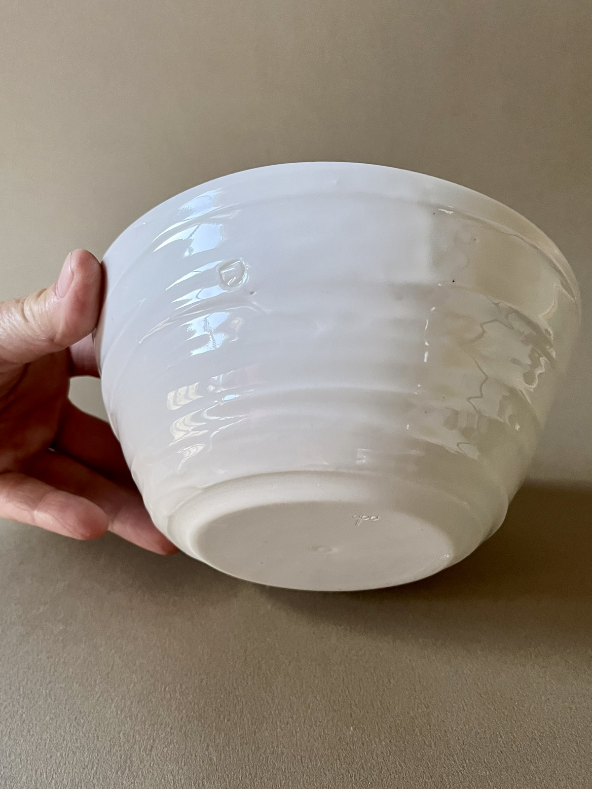 Bol Purete en porcelaine blanche retourné tenu en main, pied tournassé