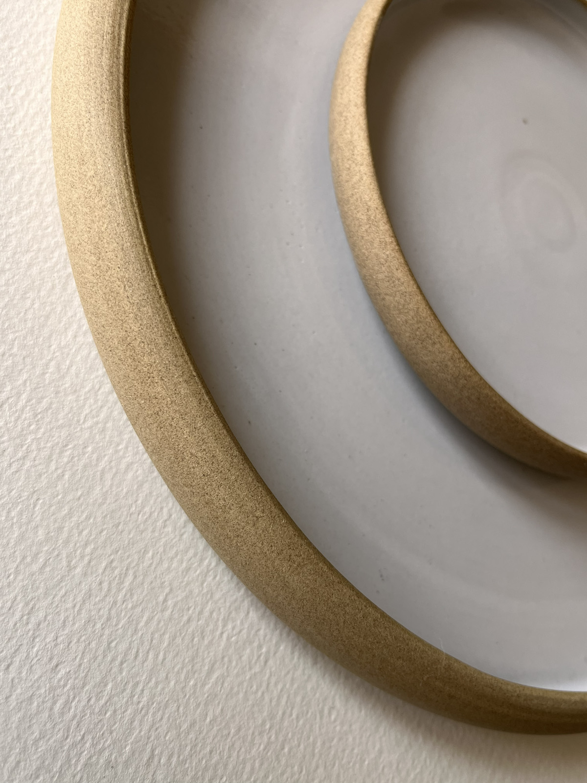 Gros plan sur les bords en grès brut de deux assiettes blanches emboîtées