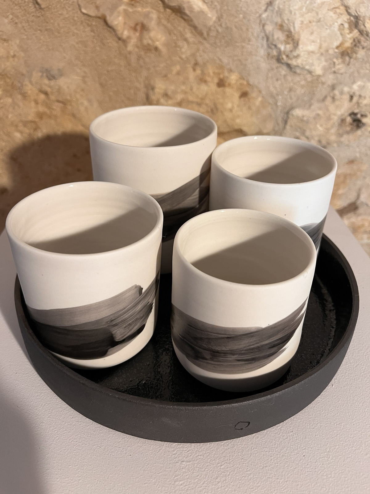 Quatre gobelets Hua en porcelaine au trait noir dans leur plateau noir, vue plongeante