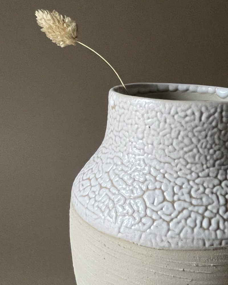 Vase Winter beige, col large en gros plan Gros plan sur le col large émaillé blanc rétracté d'un vase Winter en grès beige strié, graminée