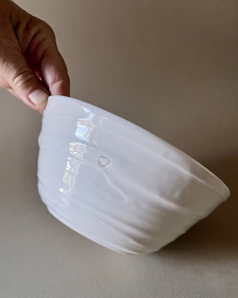 Bol Purete en porcelaine blanche tenu incliné, montrant sa paroi striée et son pied