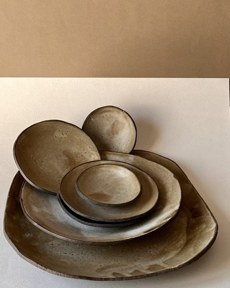 Assiettes et coupelles en grès brun émaillé beige Pile d'assiettes et coupelles en grès brun foncé à l'émail beige nuageux, formes libres