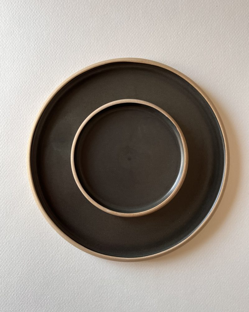 Deux assiettes rondes en grès émaillé noir mat au bord laissé brut, emboîtées, vues de dessus