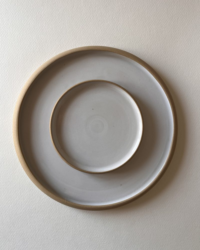Deux assiettes rondes émaillées blanc à bord de grès brut, emboîtées, vues de dessus