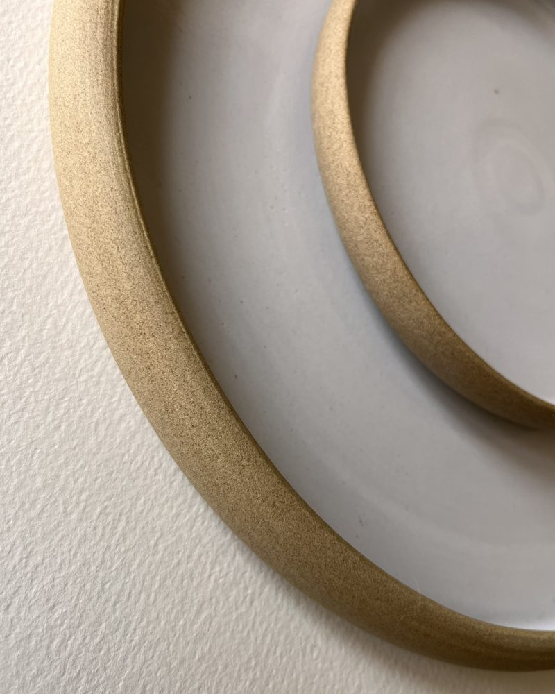 Gros plan sur les bords en grès brut de deux assiettes blanches emboîtées